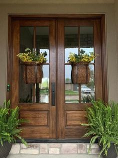 two potted plants sitting on the side of a wooden door with glass panes