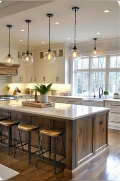 a kitchen island with stools and lights hanging from the ceiling