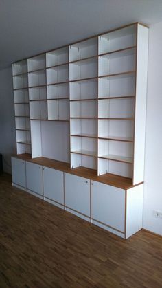 an empty room with white bookcases and wood flooring on the side wall