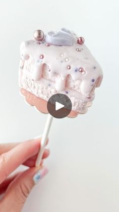 someone is holding a tiny cake on a stick