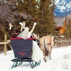 a bride and groom riding in a horse drawn sleigh