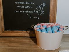 a bucket filled with blue and pink crayons sitting next to a chalkboard