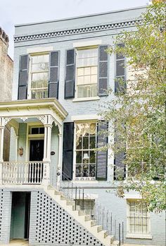 a large white house with black shutters and stairs