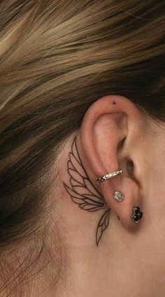 a woman's behind the ear has a small wing tattoo on her left side