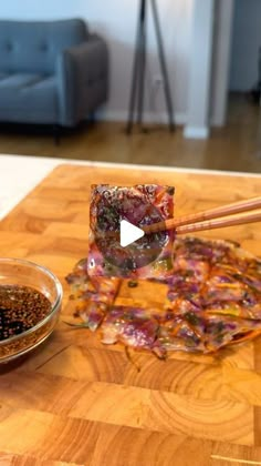 chopsticks are being used to stir food on a wooden table in a living room