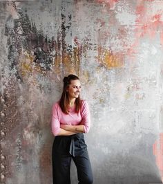 a woman standing in front of a wall with her arms crossed