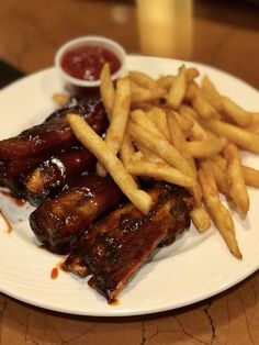 ribs and french fries on a plate with ketchup