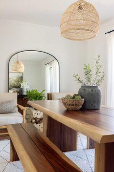 a wooden table sitting in front of a mirror on top of a floor next to a white couch