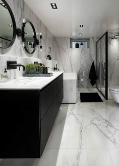 a large bathroom with marble walls and flooring, black cabinets and mirrors on the wall