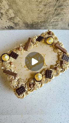 a cake decorated with gold and chocolates on top of a white countertop next to a wall