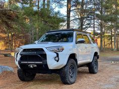 a white toyota 4runner is parked in the woods