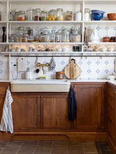 a kitchen filled with lots of clutter and cooking utensils on top of wooden cabinets