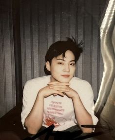 a young man sitting in front of a mirror with his hands on his chest and looking at the camera