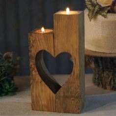 a wooden candle holder with a heart cut out of it next to a wedding cake