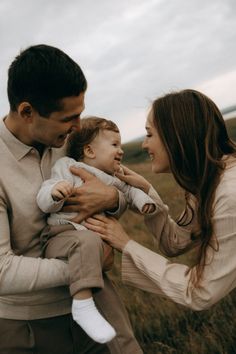 a man and woman holding a baby in their arms