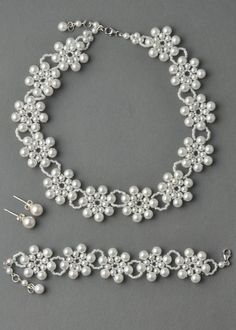 a white necklace and earring set with pearls on the bottom, along with a pair of earrings