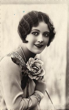 an old black and white photo of a woman holding a rose