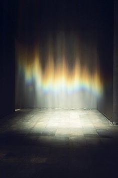 an empty room with a checkered floor and rainbow colored light coming from the ceiling