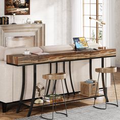 a table with stools and a laptop on it in front of a couch next to a fireplace