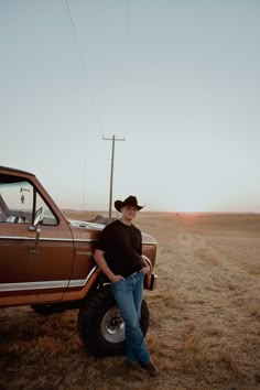 a man standing next to a truck in the middle of a dry grass covered field