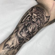 a man's leg with a tiger tattoo on it and an inked hand