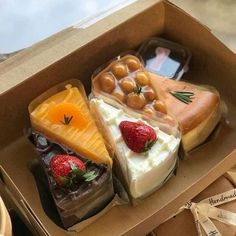 a box filled with assorted desserts on top of a wooden table next to a basket