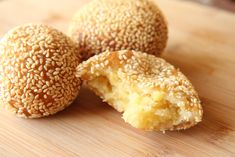 three sesame seed donuts on a cutting board