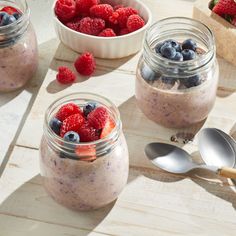 three small jars filled with fruit and oatmeal on top of a wooden table