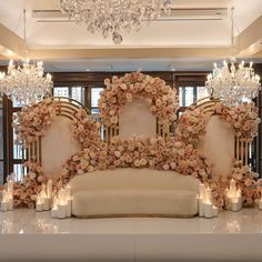 an elaborately decorated couch with candles and flowers on the back is in front of a chandelier