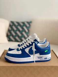 Embrace iconic style with these statement-making sneakers inspired by the legendary Louis Vuitton x Nike Air Force 1 collaboration. The vibrant blue leather upper, accented with the signature Louis Vuitton monogram, exudes luxury and street-style cool. Off-White™-inspired details add a contemporary edge, like the quoted "AIR" branding and exposed stitching. Step into the spotlight with these coveted kicks that blend high-fashion and sneaker culture. Your order arrives in a branded shoe box, comp Luxury Streetwear Sneakers With Round Toe, Luxury Round Toe Sneakers For Streetwear, Modern Custom Sneakers With Perforations For Streetwear, Blue Lace-up Sneakers With Logo Print, Modern Blue Custom Sneakers For Streetwear, Blue Perforated Sneakers For Streetwear, Blue Sneakers With Perforations For Streetwear, Luxury Logo Print Sneakers For Streetwear, Designer Streetwear Sneakers With White Sole