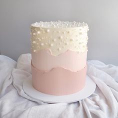 a pink and white cake sitting on top of a table next to a white cloth