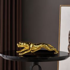 a gold animal figurine sitting on top of a black table next to a framed photo