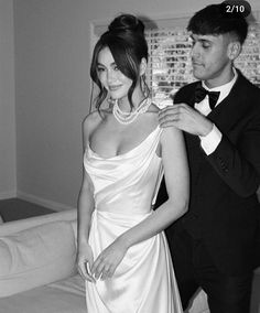 a man helping a woman put on her wedding dress