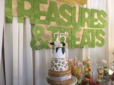 a table topped with a cake covered in lots of toppings next to a sign that reads treasures & treats