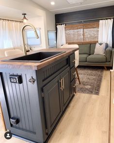 a kitchen island in the middle of a living room with a couch and window behind it