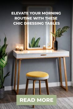 a desk with a mirror, stool and candles on it in front of a gray wall