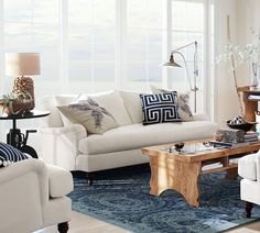 a living room filled with white furniture and lots of windows