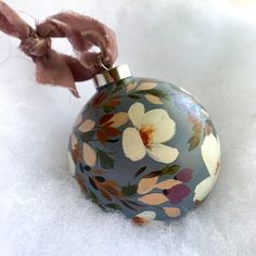 a glass ornament with flowers painted on it's side sitting in the snow