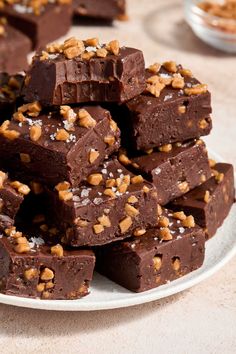 a white plate topped with pieces of chocolate covered in walnuts and sea salt on top of a table