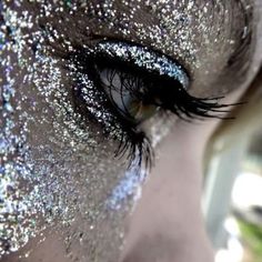 an eye with glitter on it and blue eyeshade in the center, looking into the distance