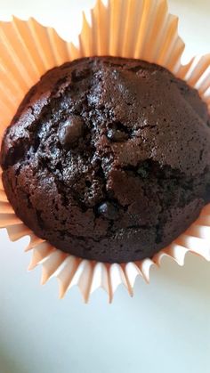 a chocolate muffin sitting on top of a white paper cupcake wrapper,