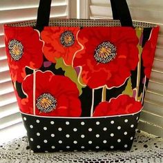 a red and black flowered bag sitting on top of a white lace doily