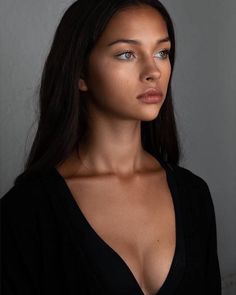 a woman with very large breast posing for the camera in black top and long dark hair