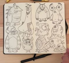 an open notebook with drawings of different cartoon characters on it and a pen next to it