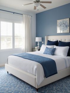 a bedroom with blue walls and white bedding in the center, along with a ceiling fan