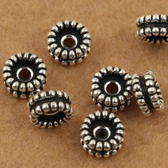 five silver bead caps on a brown surface