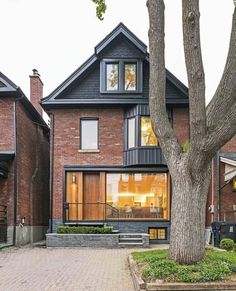 a brick house with large trees in the front yard