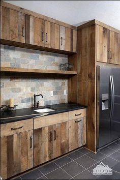 a kitchen with wooden cabinets and black counter tops in front of a stainless steel refrigerator