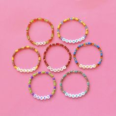 six bracelets with the word love spelled in different colors and sizes on a pink background