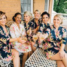 the bridesmaids are all dressed in matching robes and holding glasses of champagne together